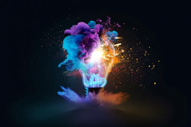 A lightbulb bursting open with bright streams of colored ink and sparks