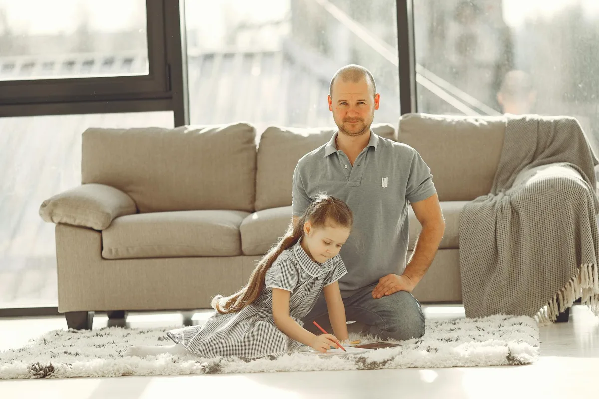 A child playing on a living-room rug, surrounded by sunlight and dust motes.