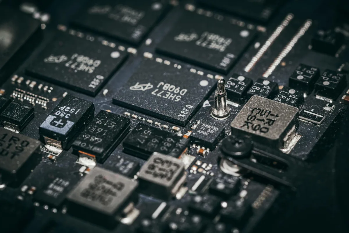 A close macro photograph of electronic microchips and surface-mount components on a dark circuit board.
