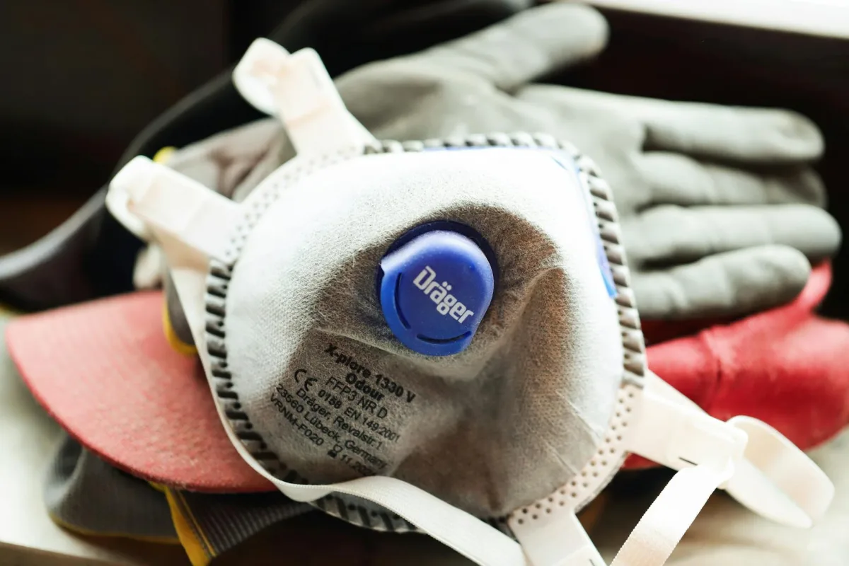 Three respirators on a counter: a cup-shape N95, a fold-flat KF94 with ear loops, and a surgical procedure mask, photographed against a neutral background.