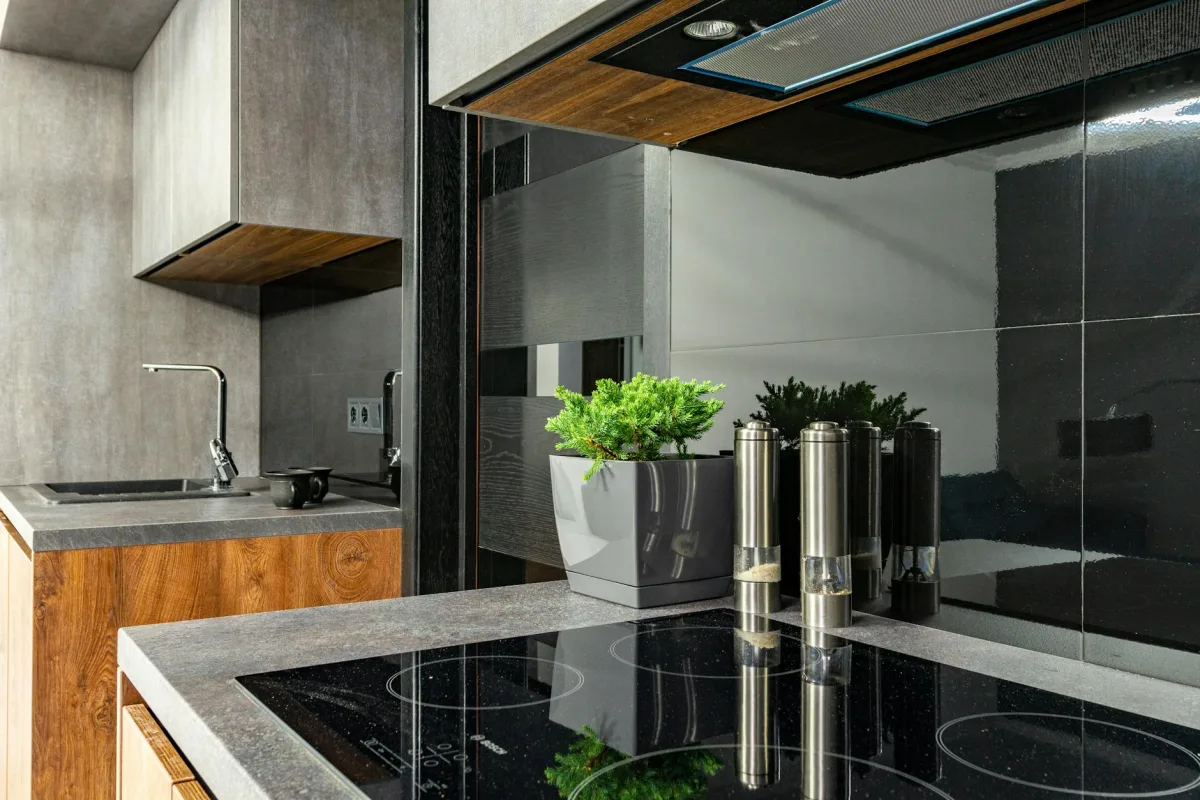 A kitchen showing a recently installed induction cooktop replacing a gas range, with an exhausted range hood overhead and a Terrestream sensor visible.