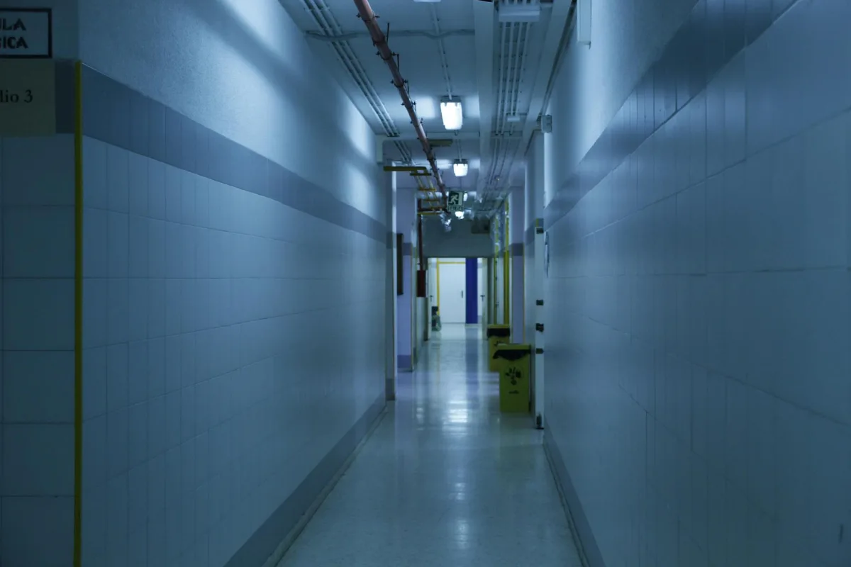 A long fluorescent-lit office hallway with closed doors on both sides.