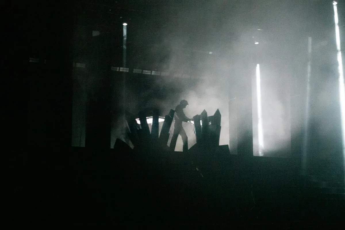A trail of vapor rising into a beam of sunlight in a darkened room.
