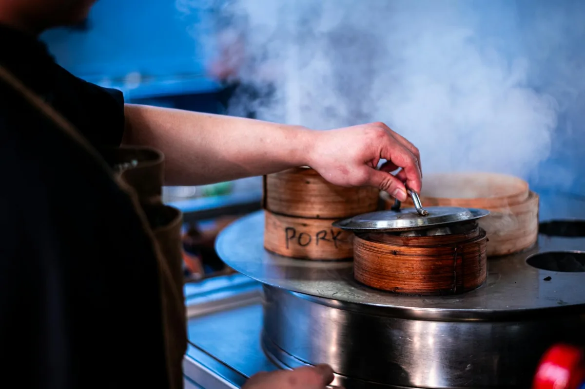A wisp of steam rising from a frying pan in a softly-lit kitchen.