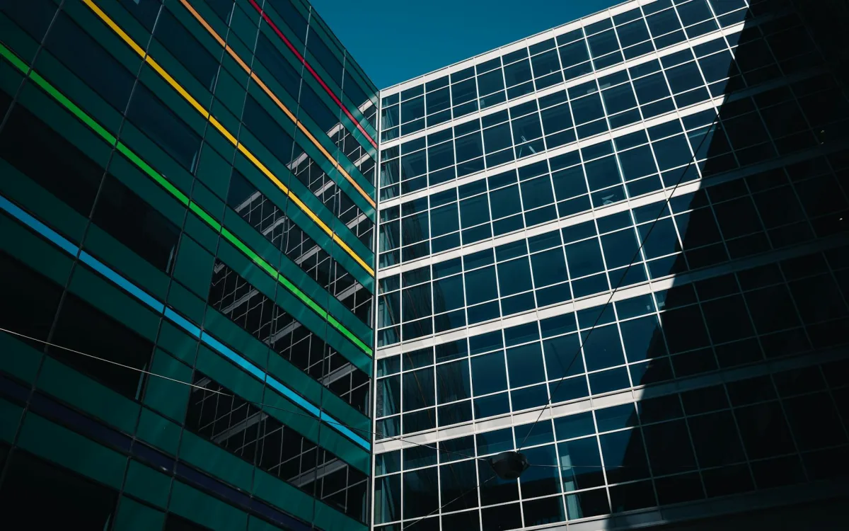 A glass-and-steel commercial office building façade with a leaf-pattern shadow.