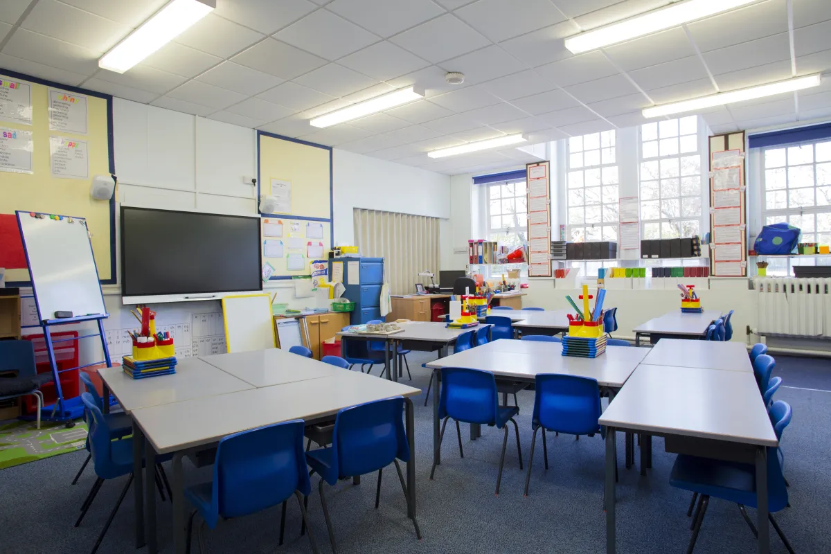 Bright classroom with desks, books, and a chalkboard